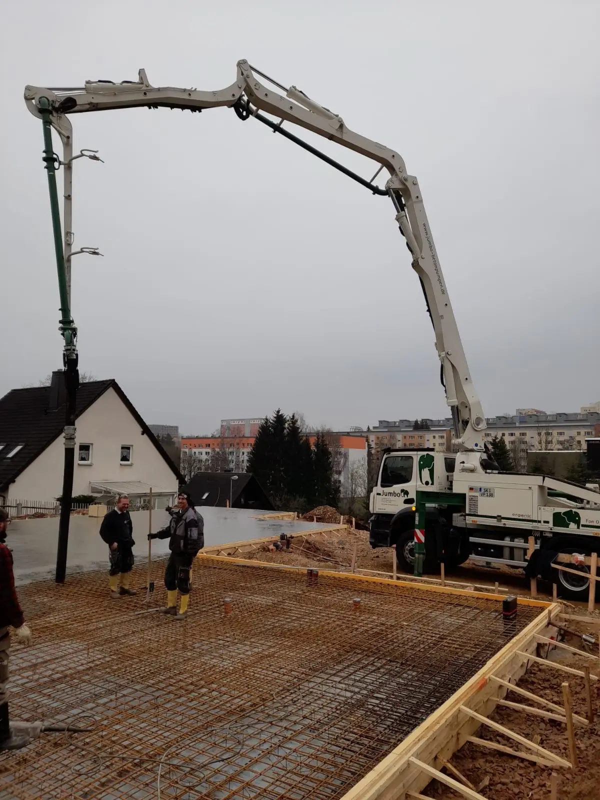 Ausleger der Betonpumpe über der vorbereiteten Bodenplatte
